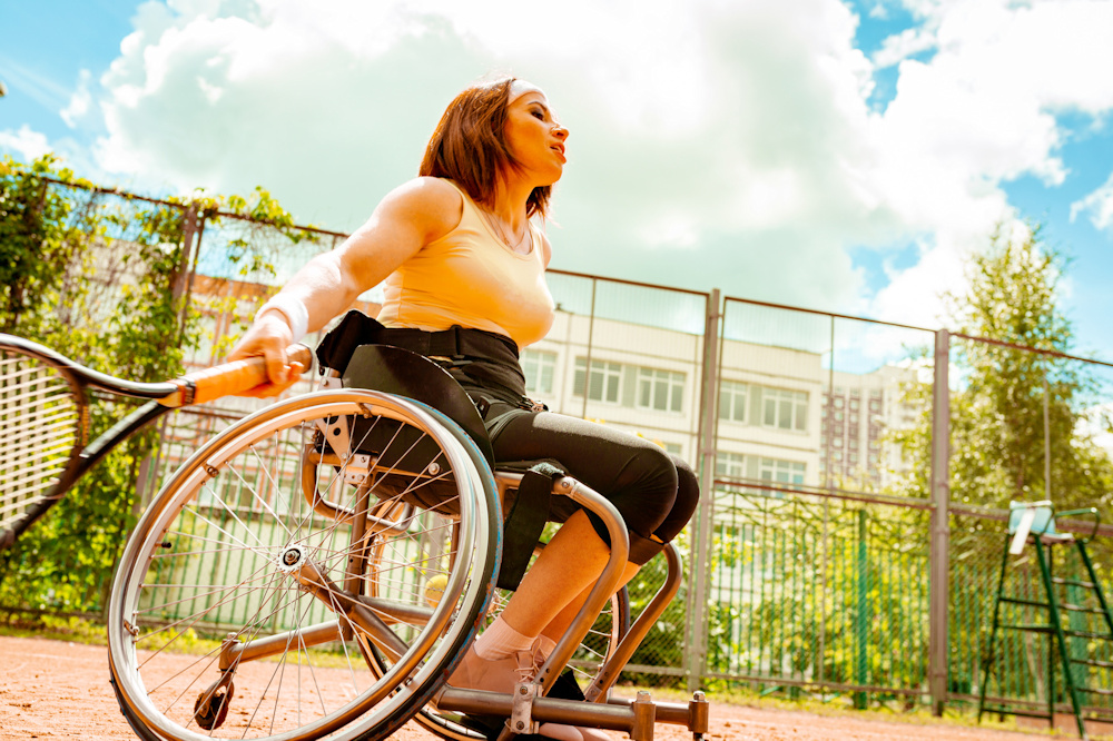 Disabled young woman on wheelchair playing tennis on tennis court